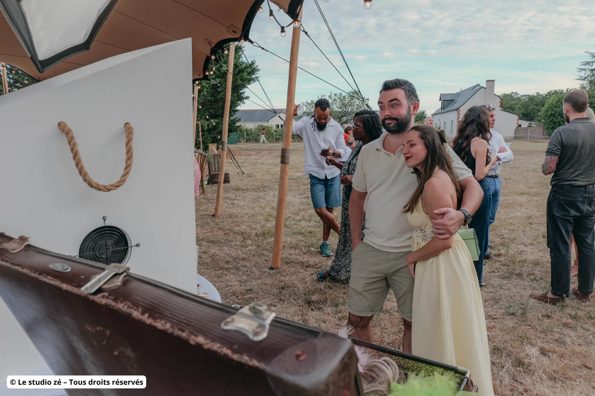 Invités posant devant le photobooth Pose N Smile avec la valise d'accessoires lors d'une réception sous tente près de Tours