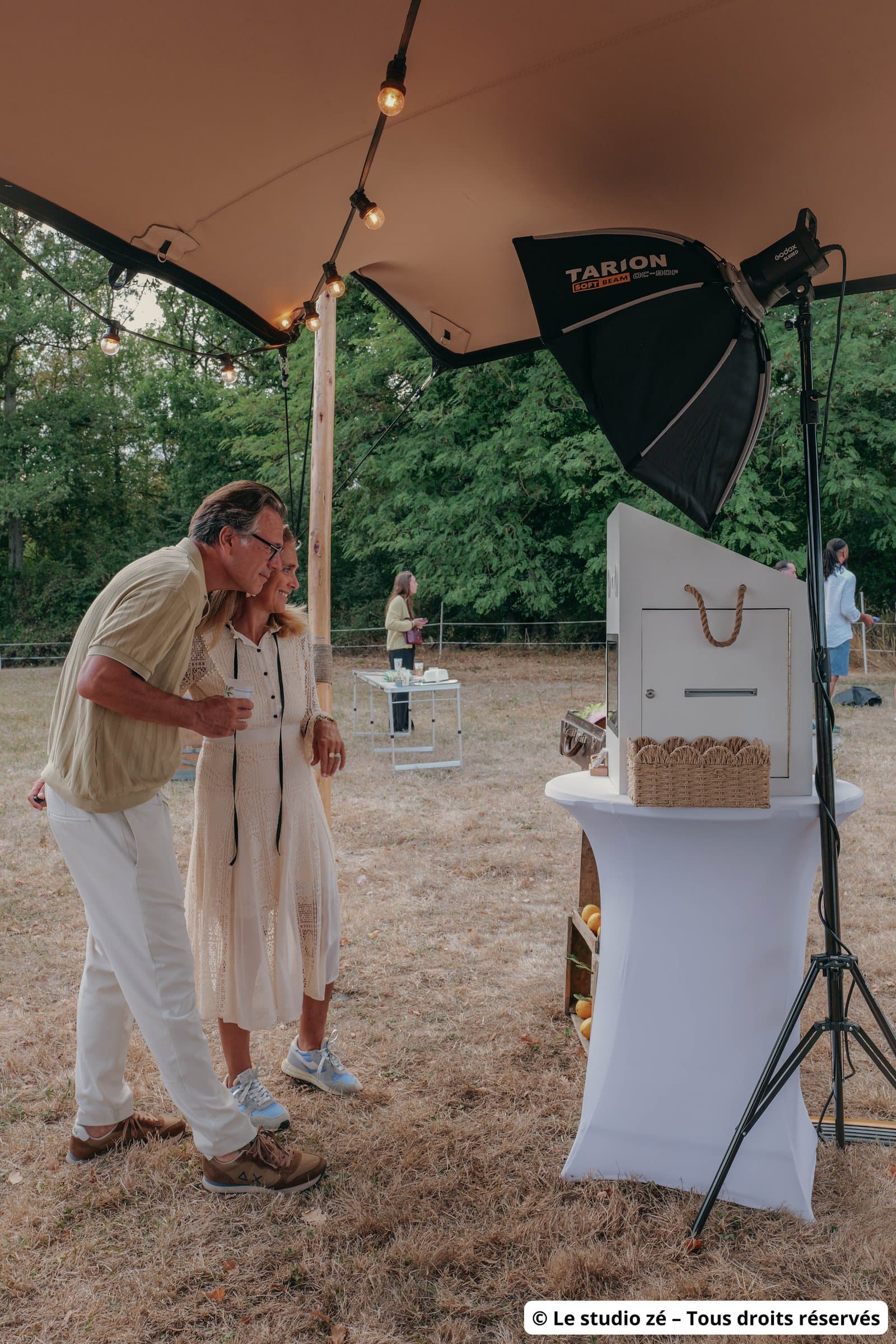 Couple devant le photobooth Pose N Smile installé sur un mange-debout avec éclairage studio lors d'une réception en extérieur en Touraine